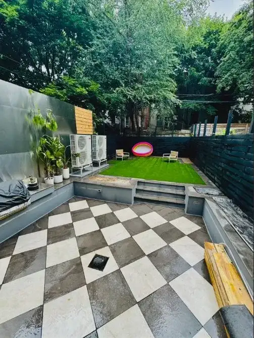 Brooklyn brownstone backyard transformation with checkerboard paver patio and raised synthetic turf lounge by Turf Boss Construction