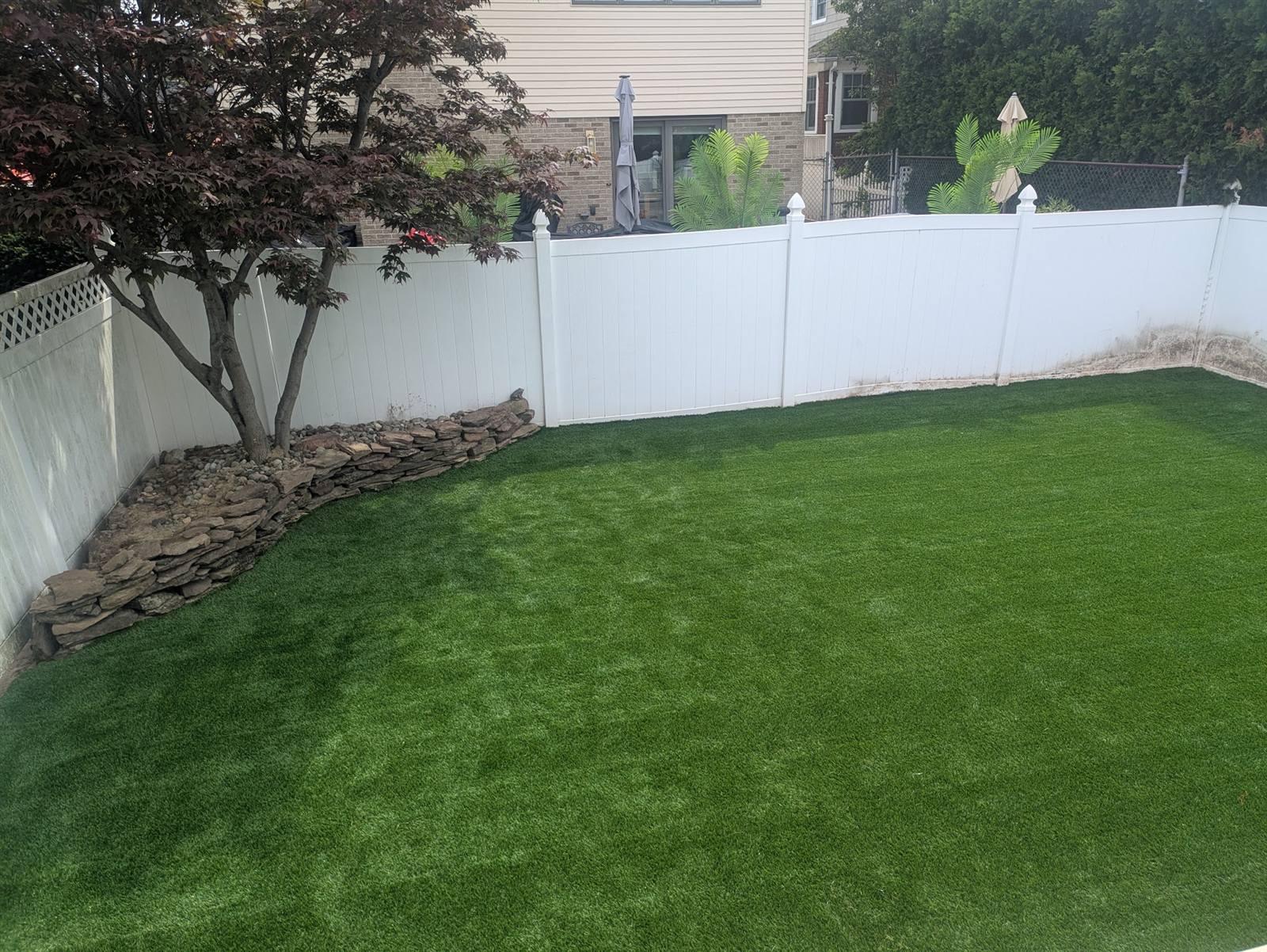 Lush premium synthetic turf lawn with stone border installed by Turf Boss Construction