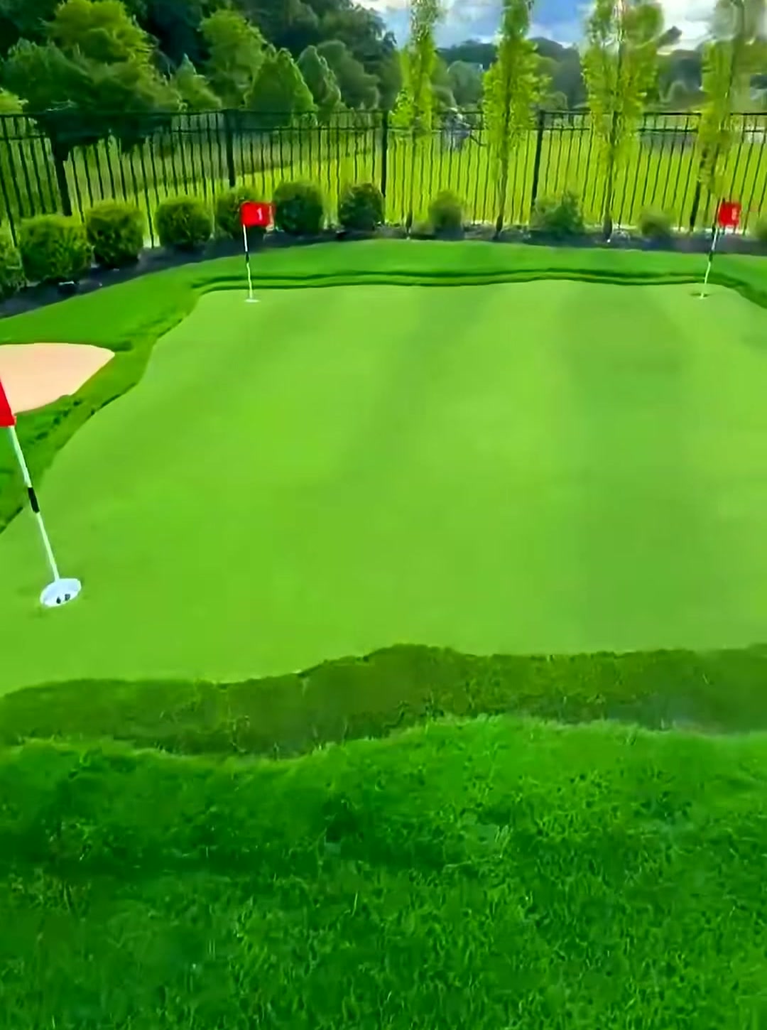 Estate backyard putting green with sand bunker and red flags installed by Turf Boss Construction
