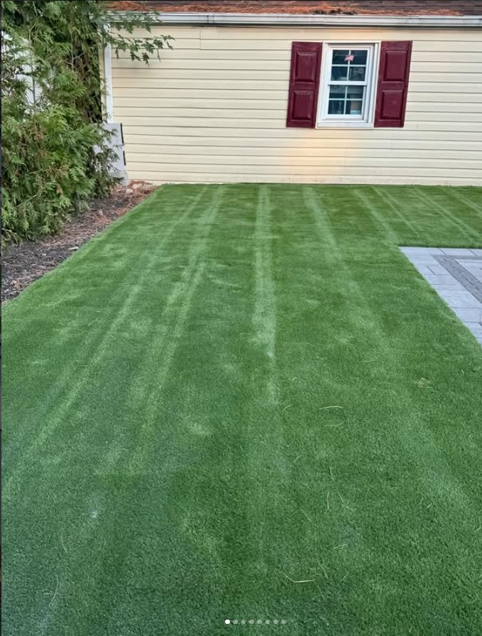 Residential backyard turf installation with stone paver border