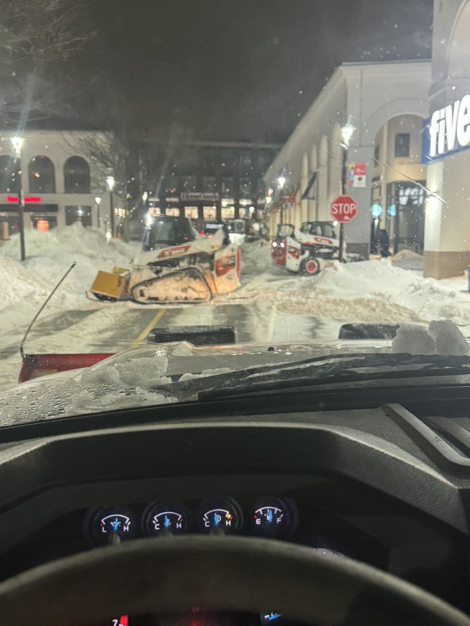 Bobcat skid steers removing accumulated snow at a commercial town center parking lot